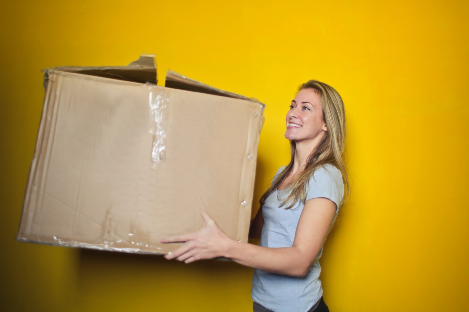 Smiling woman carrying a cardboard moving box